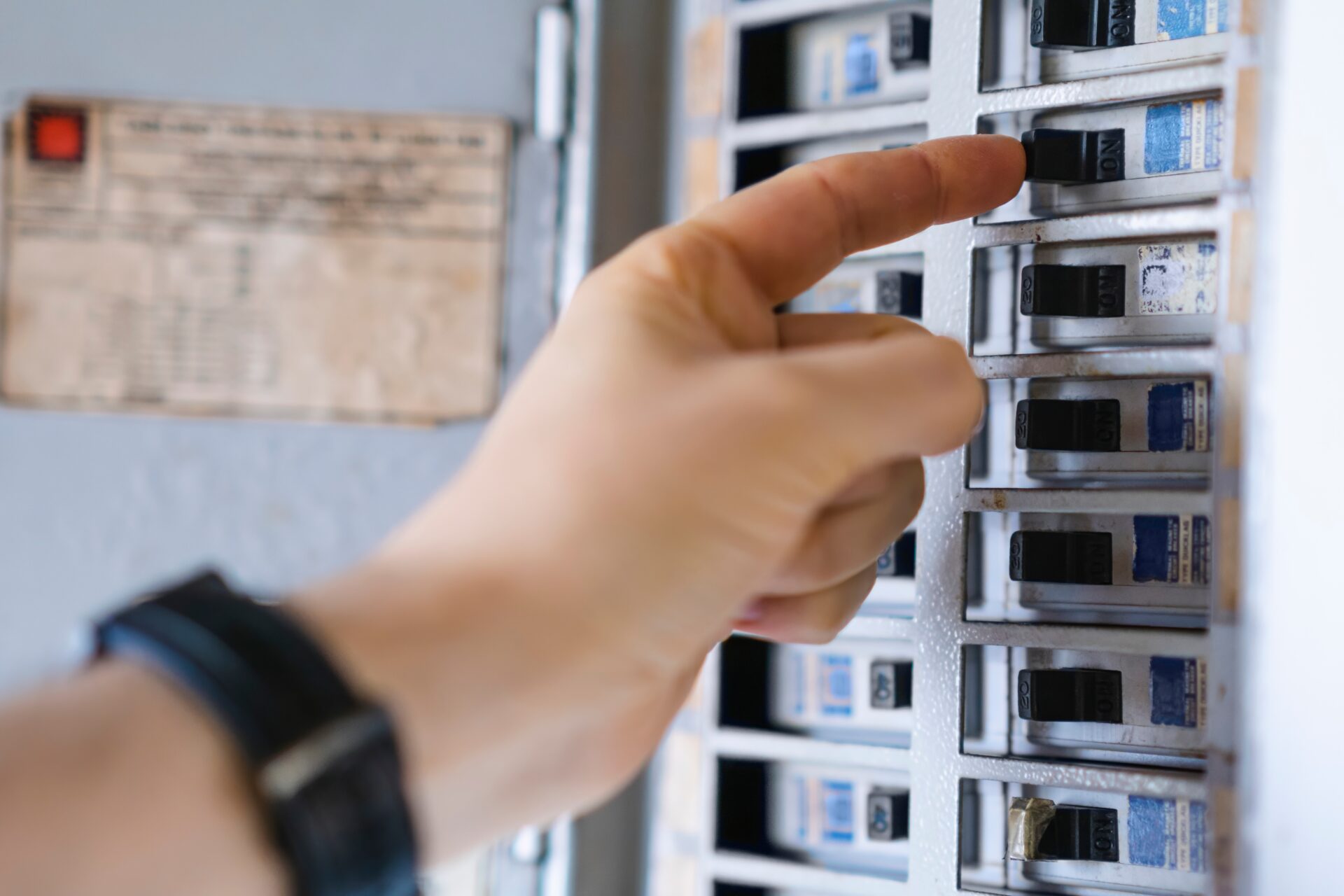 Hand turning on electricity breaker.