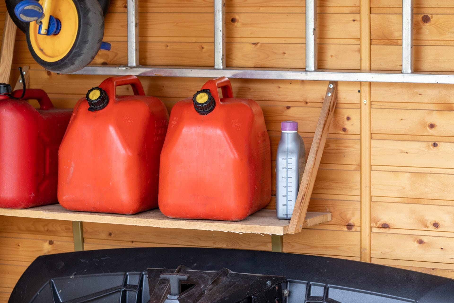 Cans of gasoline in a garage that are expired and need to be disposed of properly