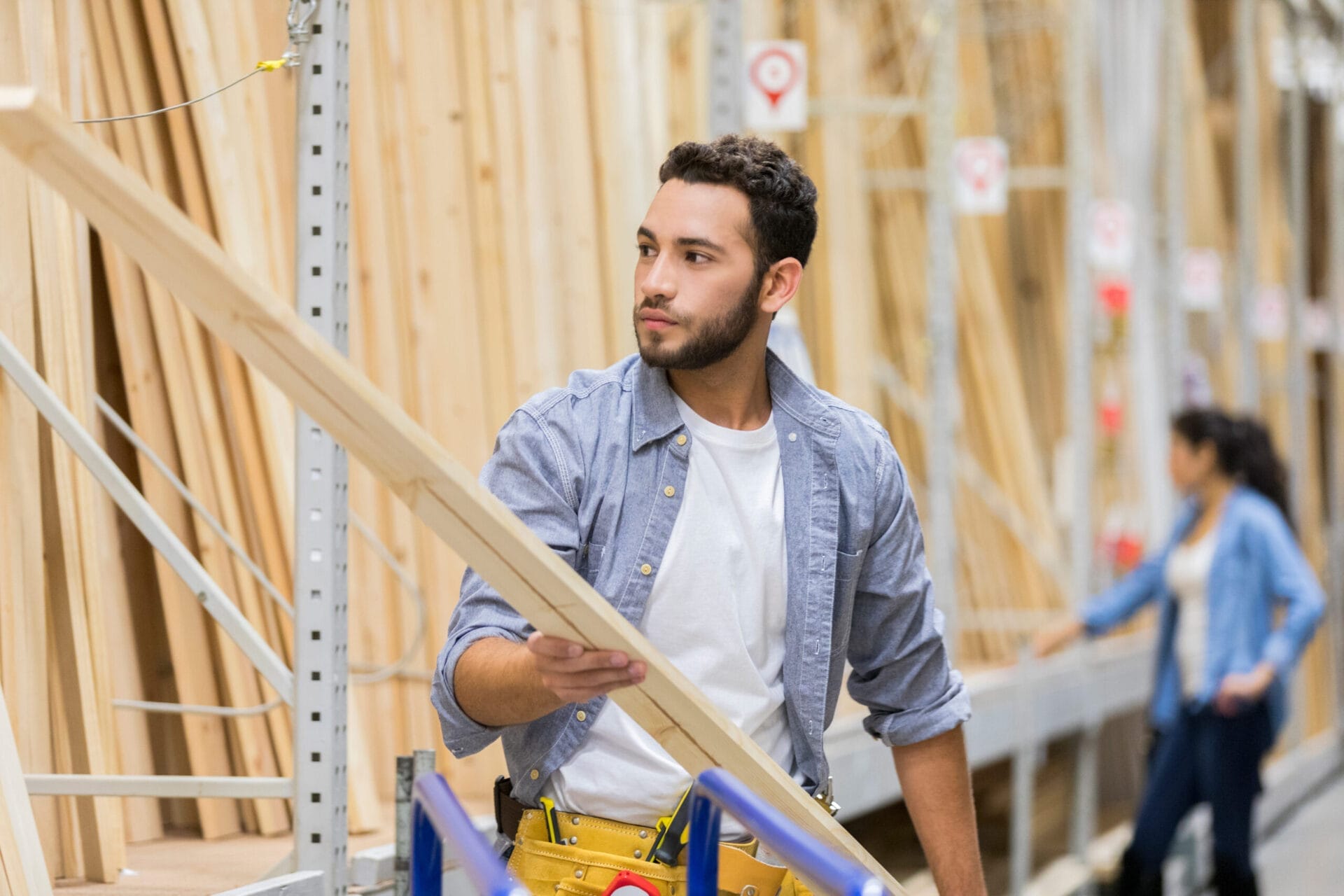 A man at a lumber store looking at a board of wood.