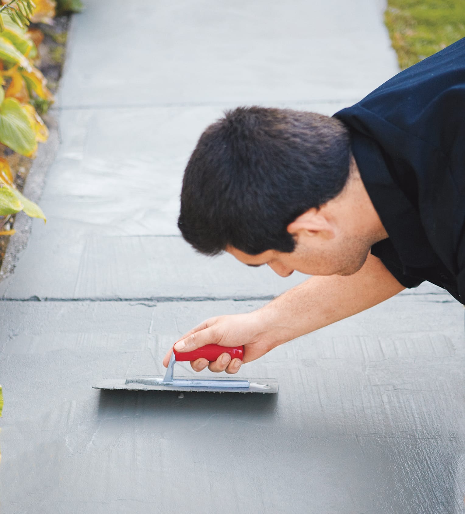 Man resurfacing a concrete walkway.