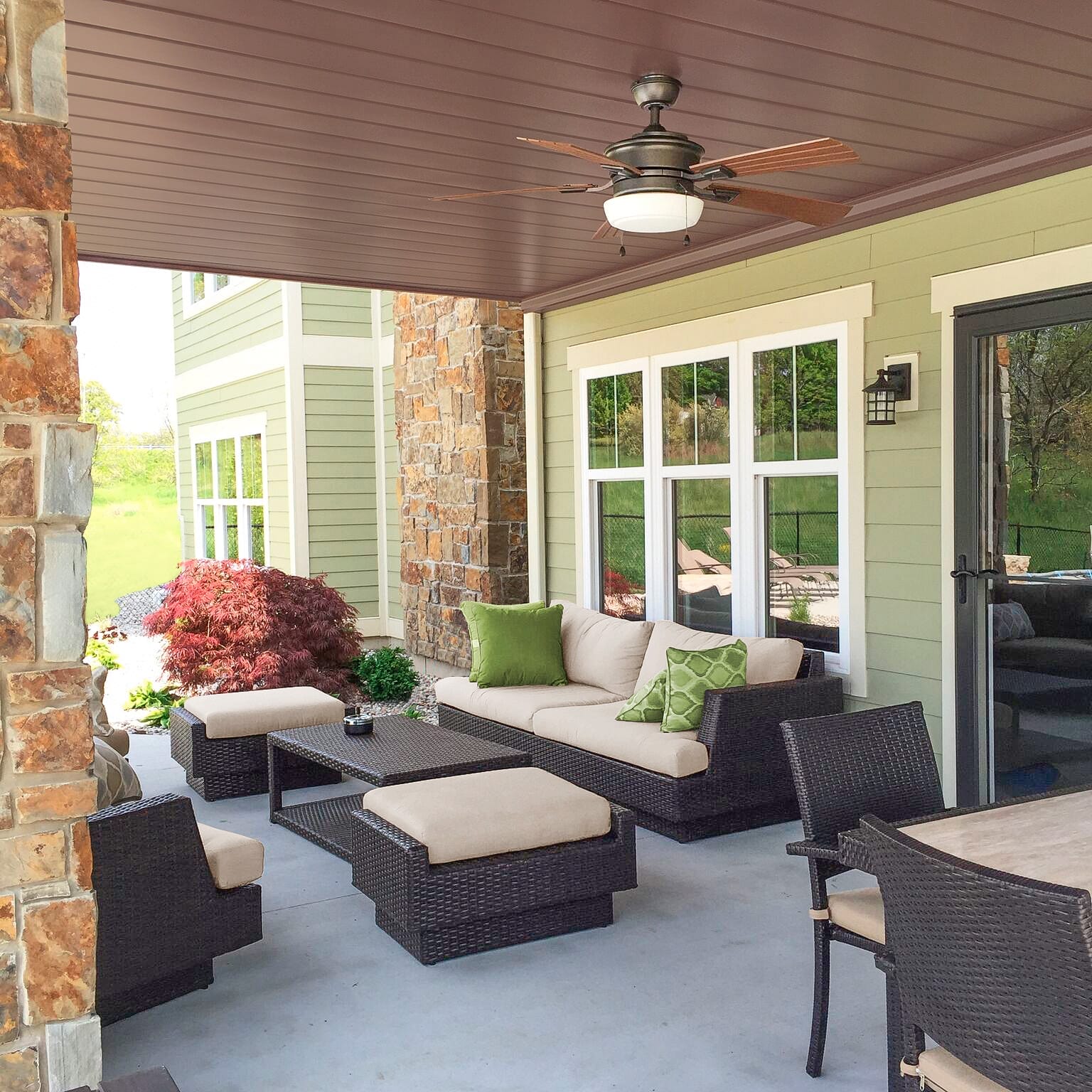 Covered patio with outdoor furniture and ceiling fan under a raised deck.