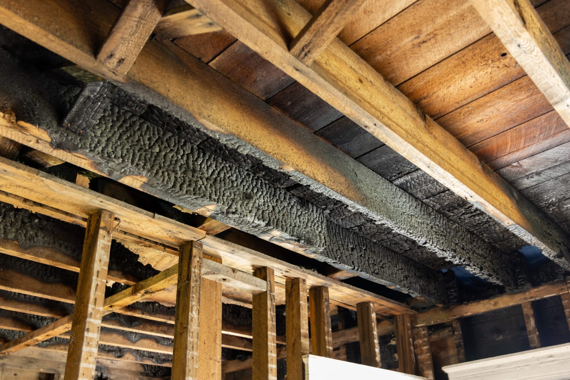 Charred ceiling joists in a second-floor room show the fire damage.
